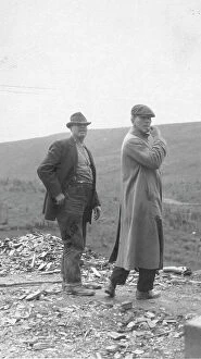 Overcoat Collection: Two men standing near a small pile of rubble, in a field, between c1900 and 1916. Creator: Unknown