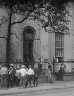 Men standing or sitting in front of the former Bank of Louisiana, 334 Royal Street... c1920-1926. Creator: Arnold Genthe