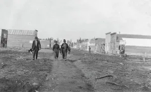 Commercial Street Prints: Three men walking down a dirt road, through town, between c1900 and 1916. Creator: Unknown