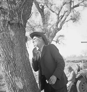 Forced Migration Collection: Migrant man shaving by roadside, on U. S. 99 between Bakersfield and the Ridge, 1939