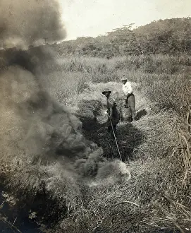 Construction Site Prints: Miraflores, the Panama Canal Zone: rising smoke as two West Indian men burn grass away