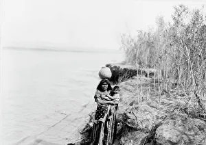 Mohave woman carrying water on her head and holding child, c1903. Creator: Edward Sheriff Curtis