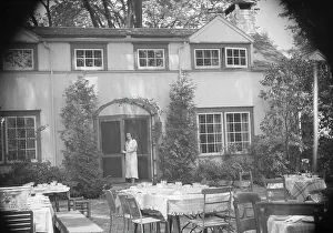 Luncheon Prints: Mrs. Mary Benson standing at the entrance to her house