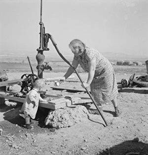 Daily Life Gallery: Mrs. Soper with youngest child at the well, Willow creek area, Malheur County, Oregon, 1939