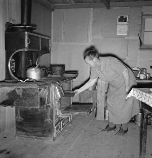 Baking Gallery: Mrs. Wardlow baking corn bread in her dugout basement home, Dead Ox Flat, Oregon, 1939