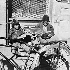 Two Negro boys reading the funnies on a doorstep, Washington, D.C. 1942. Creator: Gordon Parks