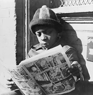 Negro youth reading a funny paper on a door step in the Southwest section, Washington, D.C. 1942. Creator: Gordon Parks
