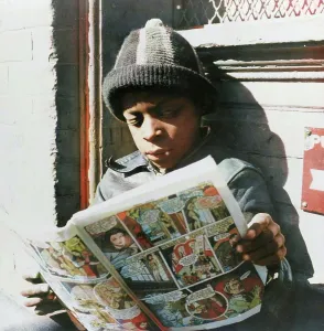 Parks Prints: Negro youth reading a funny paper on a door step in the Southwest section