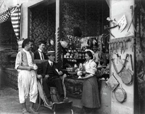 Pan-American Exposition, Buffalo, N.Y. 1901: Man in wheeled chair at souvenir shop with 4... 1901. Creator: Frances Benjamin Johnston