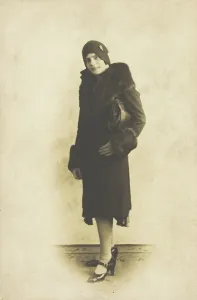 Impersonating Prints: A person poses wearing a long coat with fur trim and a hat with a brooch