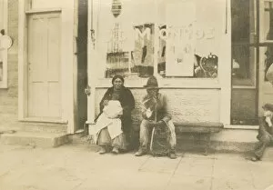 Images Dated 18th August 2021: Photograph of a man and woman sitting outside of a storefront, early 20th century
