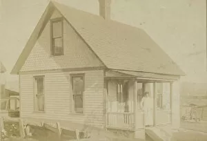 Photograph of a woman standing on the porch of a house, early 20th century