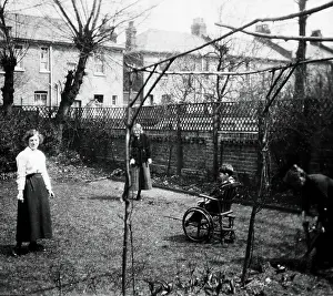 Disability Prints: A physically disabled boy sitting in a wheelchair in the back garden of a semi