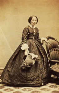 Portrait of older woman, standing, holding bonnet, c1860. Creator: CK Bill