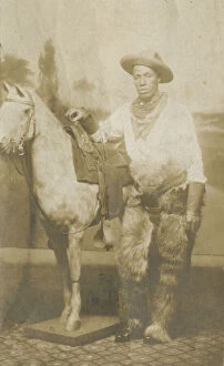 Portraits Gallery: Postcard of a man posing in a Western scene in a photography studio, early 20th century