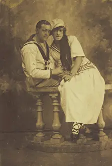 Affectionate Prints: Two sailors, one in drag, embracing while sitting on a stage balcony