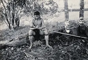 Southeast Asia Prints: Sarawak: a Kenyah worker tying a spearhead to a blowpipe, c1900. Creator: Unknown