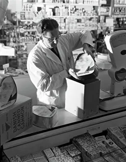 Shopkeeper Gallery: Shopkeeper unpacking canned gammon joints, Mexborough, South Yorkshire, 1963. Artist