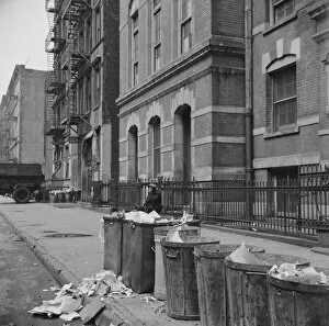 Sidewalk Gallery: Street scene showing open trash cans along the curb, New York, 1943. Creator: Gordon Parks