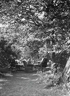 Sun Lounger Prints: Tea in the Griffin or Nissen Garden, 1931 June 14. Creator: Arnold Genthe