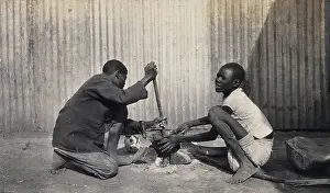 Crouching Prints: Umtali, Zimbabwe: two African boys stirring a cooking pot, 1905. Creator: J Lomas