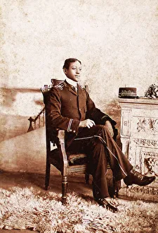 Roche Prints: Uniformed man seated, on the mantlepiece is his cap