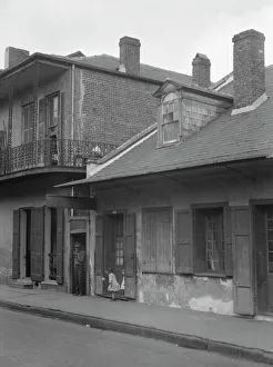 Balcony Rail Prints: View from across street of two children standing in a doorway in the French Quarter
