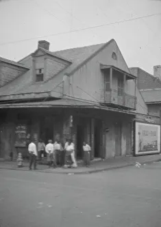 View from across street of a group of men on a street corner, New Orleans, between 1920 and 1926. Creator: Arnold Genthe