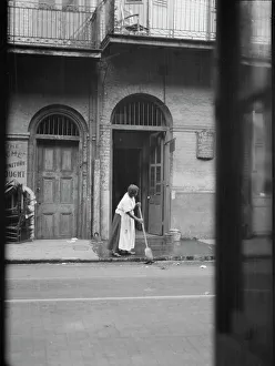 Cleaning Prints: View from across street of a woman cleaning the sidewalk
