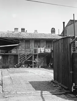 Balcony Rail Prints: View of two-story dwellings with laundry hanging over balcony railing