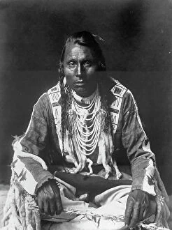 Ermine Collection: Wades in Water, Piegan Indian, full-length portrait, seated on floor, facing front..., c1910