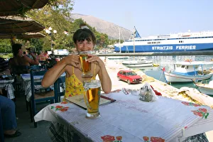 Kefalonia Prints: Woman enjoying a drink in a harbourside taverna, Poros, Kefalonia, Greece
