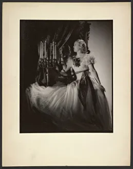 Candlestick Prints: Woman lighting candelabra, 1930s. Creator: Gunther Krampf