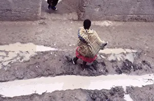 West African Prints: Woman in muddy street, Mopti, Mali, 1990. Creator: Amanda Waite