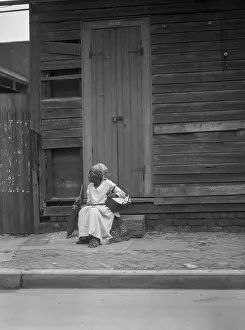 Woman sitting on steps holding a basket, New Orleans, between 1920 and 1926. Creator: Arnold Genthe