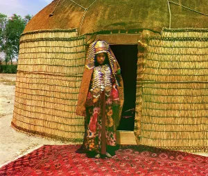 Nomadic Prints: Woman in traditional dress and jewelry standing on rug in front of yurt