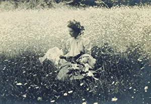 Daisy Prints: Woman with wreath of leaves in her hair sitting in a field of daisies