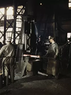 Working with a small steam drop hammer, blacksmith shop, Santa Fe RR shops, Topeka, Kansas, 1943. Creator: Jack Delano