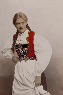 Plait Prints: A young Norwegian woman, posing in a photographic studio wearing peasant dress