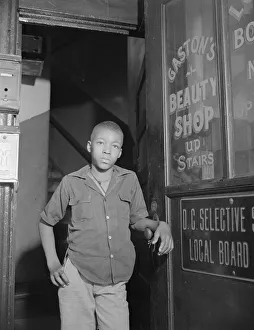 Doorway Collection: Youth waiting for a newspaper delivery truck, Washington, D.C. 1942. Creator: Gordon Parks